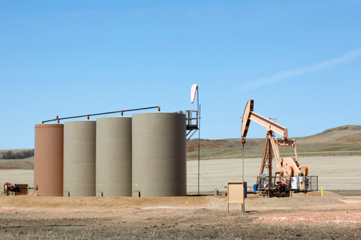 Oil pump standing tall in a vast field under the clear blue sky.